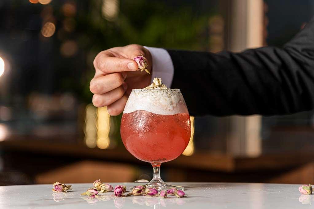 Aleph Doha Residences, Curio Collection By Hilton מסעדה תמונה A bartender adding a rose petal to a cocktail